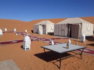 a picnic table in front of tents in the desert at Afraklie Camp in Merzouga +16 photos
