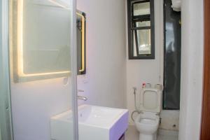 a white bathroom with a toilet and a sink at Pwj Realty Apartments in Lekki +2 photos