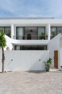 a white house with a fence and a palm tree at Elements Villa B1 - Rooftop, Pool & 5-Min to Beach in Bingin Beach