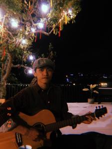a man playing a guitar at a table at night at Dalat inn homestay hẻm 48 hà huy tập in Teurnoum