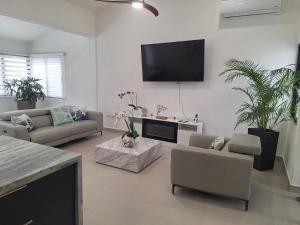 a living room with couches and a flat screen tv at White House Mansion in San Felipe de Puerto Plata