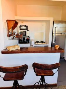 a kitchen with a counter with two stools in front of it at Pousada Azul do Mar in Búzios