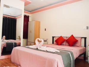 two swans are sitting on two beds in a room at JLB Resort and Tours,Mango Rooms in Valdez