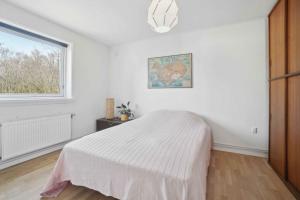 une chambre blanche avec un lit et une fenêtre dans l'établissement Rummeligt Feriehus På Stor Naturgrund, à Langedeby