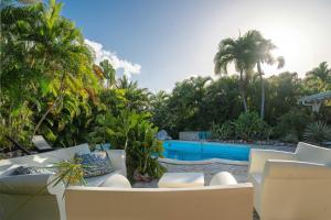 a patio with white chairs and a swimming pool at Villa Secrète in Saint-François