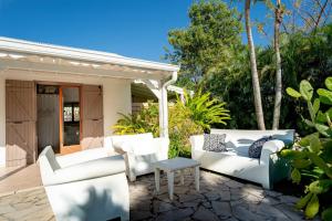 a patio with white chairs and a table at Villa Secrète in Saint-François