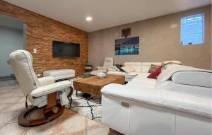 ein Wohnzimmer mit weißen Möbeln und einer Ziegelwand in der Unterkunft Maison Piscine in Cabannes