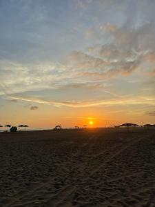 a sunset on the beach with umbrellas on the sand at Casa grande en perfecta ubicación cerca al mar in La Punta