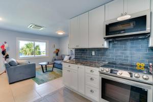 a kitchen with white cabinets and a blue tile wall at Boat Dock and Patio Canal-Front St James City Home! in Saint James City