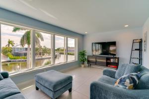 a living room with two blue chairs and a tv at Boat Dock and Patio Canal-Front St James City Home! in Saint James City