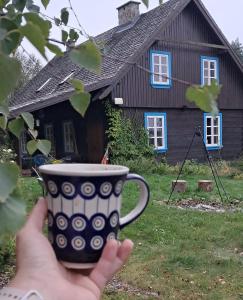 een hand die een kopje koffie vasthoudt voor een huis bij SoBądź - Po prostu bądź in Sobącz