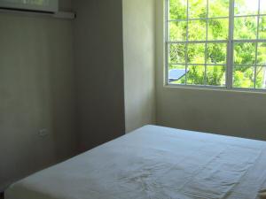 ein Schlafzimmer mit einem weißen Bett und einem Fenster in der Unterkunft 104 Batts Rock Beach Condos near UWI in Saint Michael