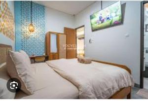 a bedroom with a large white bed and a tv at Konohagakure in Jakarta