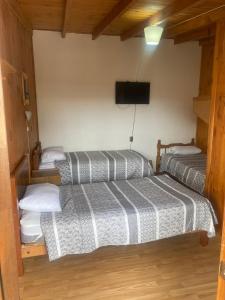 a room with two beds and a flat screen tv at Hostal Centro in Pichilemu