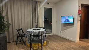 een kamer met een tafel en een tv aan de muur bij Casa Do Refugio Guest House in Covilhã