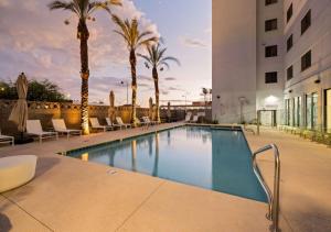 a swimming pool with palm trees and a building at Astral Desert Retreats in Mesa