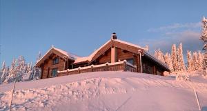 a log cabin in the snow with a pile of snow at Cozy Log Cabin With A View Over Hedmarken in Løten