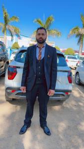 ジュネーヴにあるJassのスーツとネクタイを着た男性が車の前に立っている