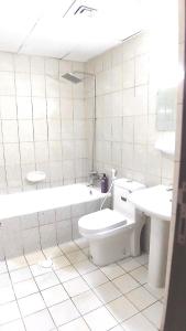 a bathroom with a toilet and a tub and a sink at Dragon Golden Apartment 2 in Dubai