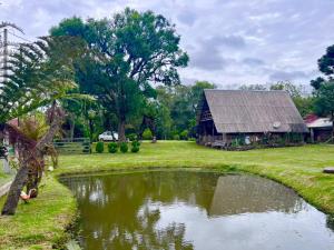 a barn and a pond in front of a house at Chalé do lago rústico in Campo Alegre