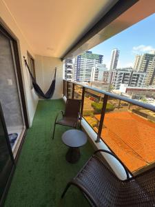 a balcony with a hammock and chairs and a view of a city at Comfort and elegance in the heart of Cabo Branco in João Pessoa