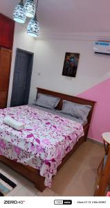 a bedroom with a bed with a pink and white comforter at manoir hoome in Bonabéri