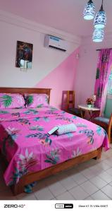 a bedroom with a pink bed with a remote control on it at manoir hoome in Bonabéri