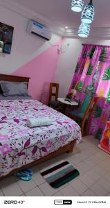 a bedroom with a bed with pink and purple sheets at manoir hoome in Bonabéri +66 photos