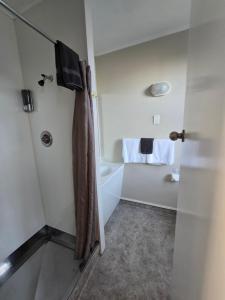 a bathroom with a shower and a bath tub at Monarch Motel in Invercargill +27 photos