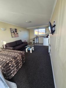 a bedroom with a bed and a living room with a couch at Monarch Motel in Invercargill