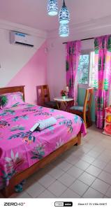 a bedroom with a pink bed and a table and chairs at manoir hoome in Bonabéri