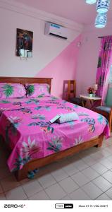 a bedroom with a pink bed with a pink comforter at manoir hoome in Bonabéri
