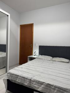 a bedroom with a large bed and a wooden door at Casa na praia de Capão da Canoa in Capão da Canoa