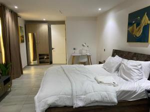 ein Schlafzimmer mit einem großen Bett mit weißen Laken und Kissen in der Unterkunft Madrid at Invent Apartments in Lekki