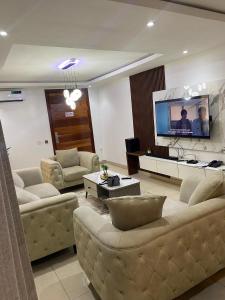 ein Wohnzimmer mit Sofas und einem Flachbildfernseher in der Unterkunft Madrid at Invent Apartments in Lekki