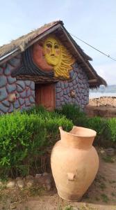 une maison avec un vase devant elle sur lequel est peint un visage dans l'établissement Cabañas lago piuray, à Chincheros 22 autres photos