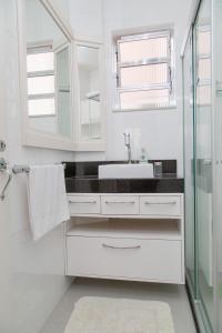 a white bathroom with a sink and a mirror at Apartamento Redenção in Porto Alegre
