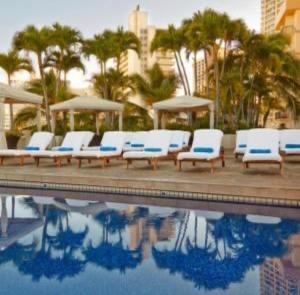 - un groupe de chaises longues blanches à côté de la piscine dans l'établissement Luana Waikiki, à Honolulu 5 autres photos