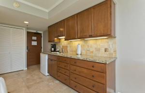 une cuisine avec des armoires en bois et un réfrigérateur blanc dans l'établissement Luana Waikiki, à Honolulu