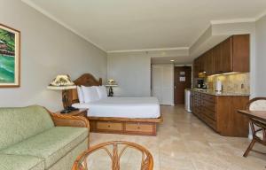 a bedroom with a bed and a couch and a kitchen at Luana Waikiki in Honolulu