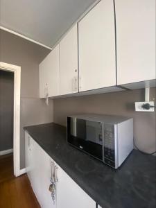 a kitchen with white cabinets and a microwave on a counter at Back Packer Style in Durban +3 photos