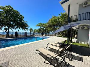 twee stoelen en een parasol naast een zwembad bij BigWave Costa Rica in Playa Hermosa
