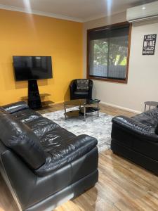 a living room with two leather couches and a flat screen tv at Benalla Apartments in Benalla