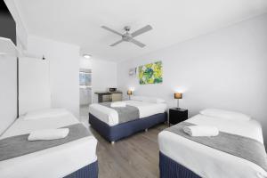 a room with three beds and a ceiling fan at Pacific Paradise Airport Motel in Pacific Paradise 
