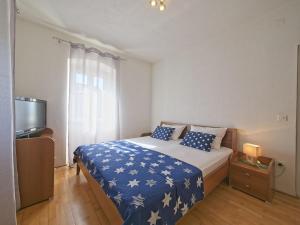 1 dormitorio con 1 cama con sábanas azules y blancas y TV en Apartments with parking space Postira, Brac - 11582, en Postira