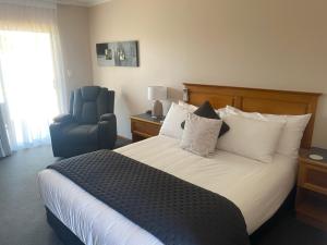 a hotel room with a bed and a blue chair at McNevins Maryborough Motel in Maryborough +55 photos