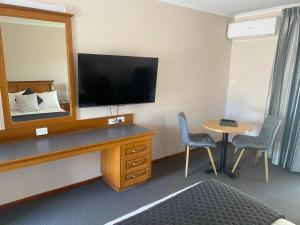 a hotel room with a tv and a mirror at McNevins Maryborough Motel in Maryborough