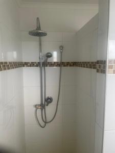 a shower in a bathroom with white tiles at scarborough QLD private accommodation E in Redcliffe