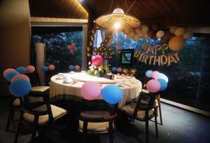 a birthday party with a table with balloons and a happy birthday sign at Zhangjiajie YOLO RELIAN Mt and River Collection-Riverside hotel with sunrise,sunset views, ticket service for attractions, afternoon tea,coffee, and laundry service in Zhangjiajie +103 photos