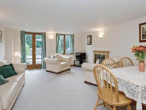 un salon avec un canapé, une table et des chaises dans l'établissement Coot Cottage, à Dilham